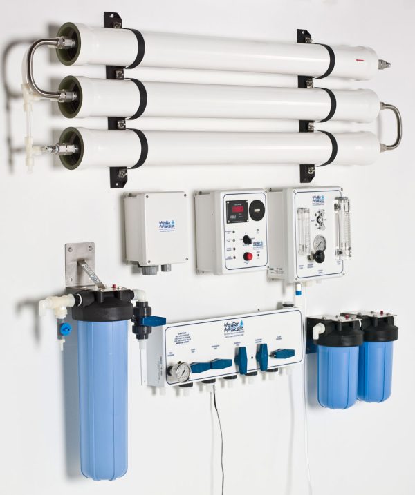 Watermakers | Advanced Reverse Osmosis Desalination Systems: Watermaker WMSQ-3000 reverse osmosis system in a modular, wall-mounted configuration. Blue and white pipes and white system boxes with dials and gauges side view.