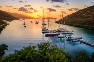 using a watermaker in the British Virgin Islands. A fleet of boats parked by the dock. Boats are sailing in the distance as the sun is setting.