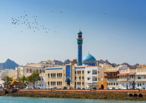 Oman using a watermaker: Oman - Muskat, Masjid Al Rasool Al A`dham Mosque with flowers and bird flying in a clear blue sky.