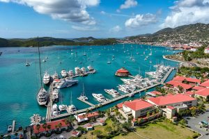 Boats of different sizes parked at the dock along the coast of the US Virgin islands. Many boats are moving in the distance. These boats are using a watermaker on their journey